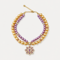 Double-strand purple and champagne pearl-effect pet necklace with a purple floral pendant on a white surface.
