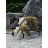 Dogs modeling olive utility overalls beside rocks.