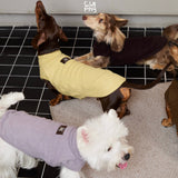 Dogs wearing yellow, lavender and plum sleeveless high-neck tops.