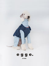 Dog wearing a blue denim vest over a light blue bodysuit.