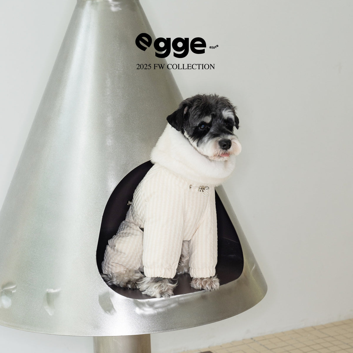 Dog wearing a cream puffer bodysuit with a white fluffy collar.