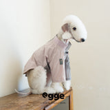 Seated dog wearing a pale pink pocket sweatshirt.