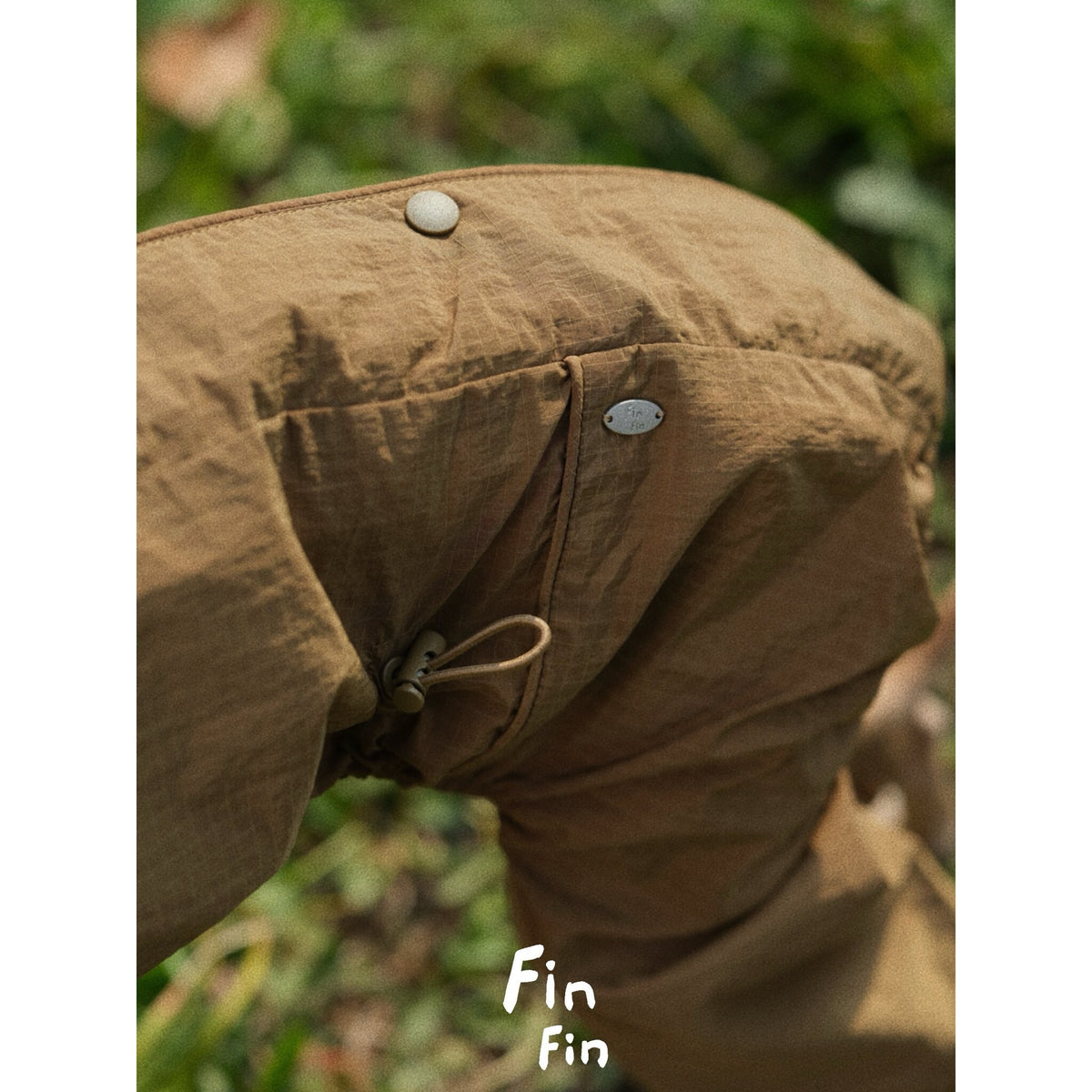 Brown dog outdoor suit fabric with snap and seam details.