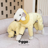 Dog wearing a yellow puffer jacket with a wraparound scarf collar.