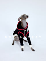 Dog modeling a black sweater with red neckline and cream cuffs.