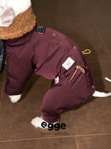 Close-up of a burgundy dog down jacket with a hood and shoulder strap.