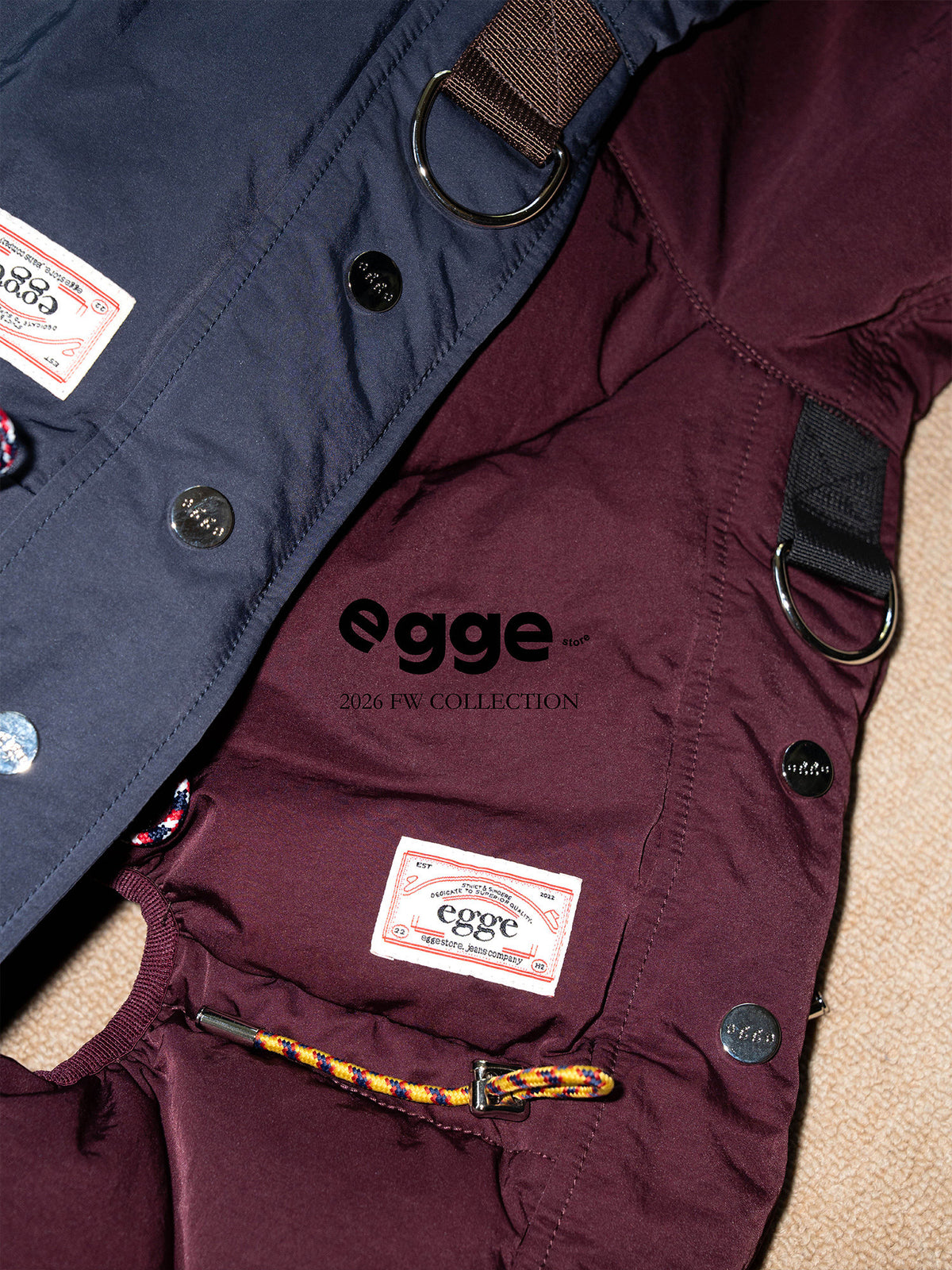 Burgundy and navy dog down jackets with buttons and leash attachment rings.
