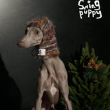 Dog wearing a multicolored knitted hood with ear openings.