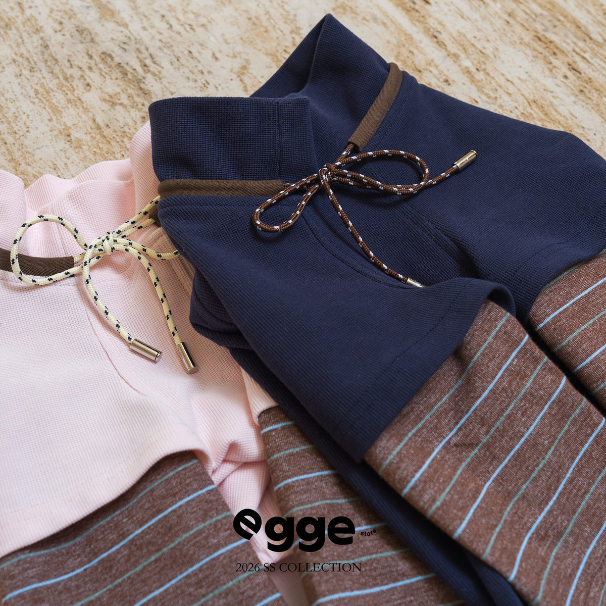 Navy and pale pink dog sweatshirts laid out to show plaid sleeves.