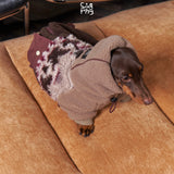 Dachshund wearing a brown hooded fleece suit with a patterned back.