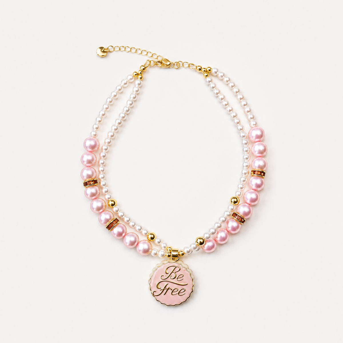 Pink and white pearl-effect pet necklace with gold-tone details and a pink Be Free pendant.